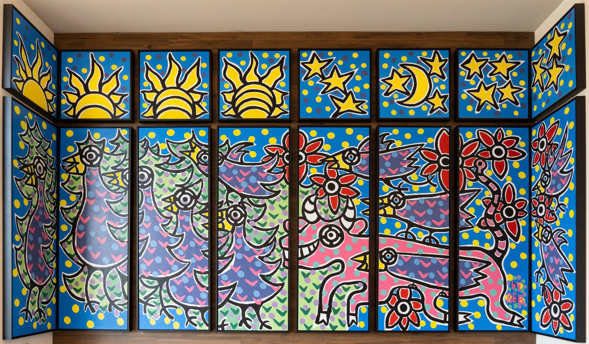 16 panel mural with yellow suns, moons, and stars with brightly colored abstract animals and flower shapes.